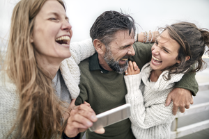 Lachende Frauen und lachender Mann am Strand