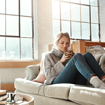 Frau sitzt mit Teetasse auf Sofa