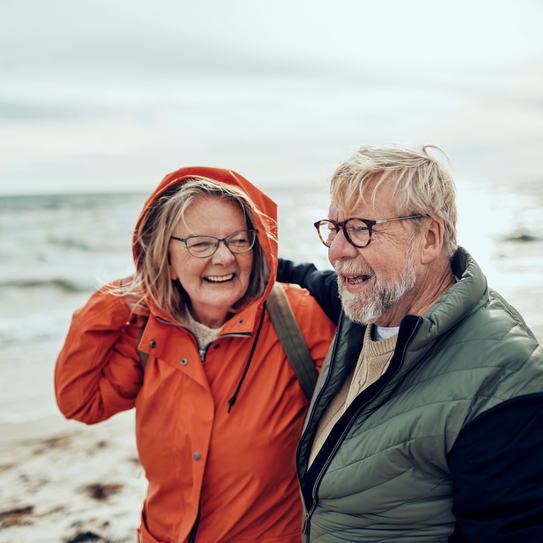 Älteres Paar in Regenjacken am Strand