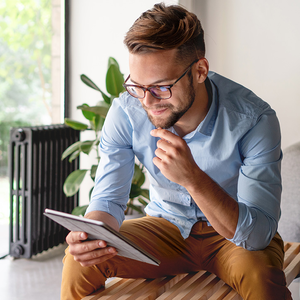 Junger Mann mit Brille schaut aufs Tablet